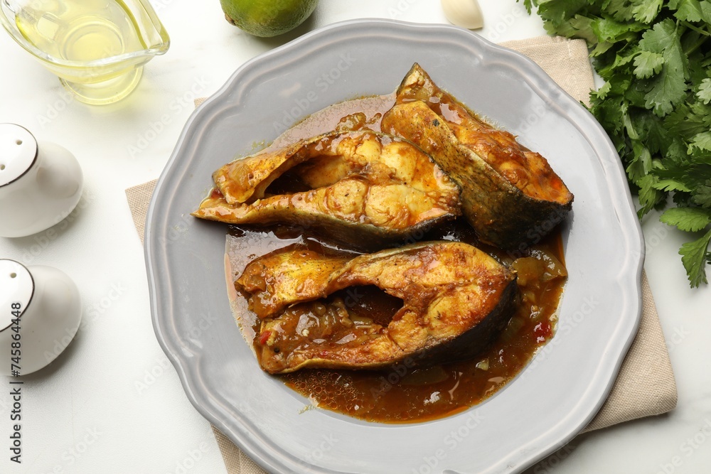 Tasty fish curry and ingredients on white marble table, flat lay. Indian cuisine Tasty fish curry and ingredients on white marble table, flat lay. Indian cuisine