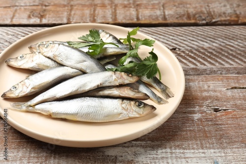 Fresh raw sprats and parsley on wooden table, closeup
