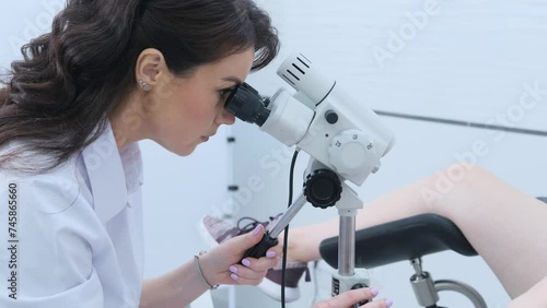 The patient and the doctor in the gynecological office during the colposcopy procedure. A gynecologist looks into a digital colposcopic microscope, studying women's diseases photo