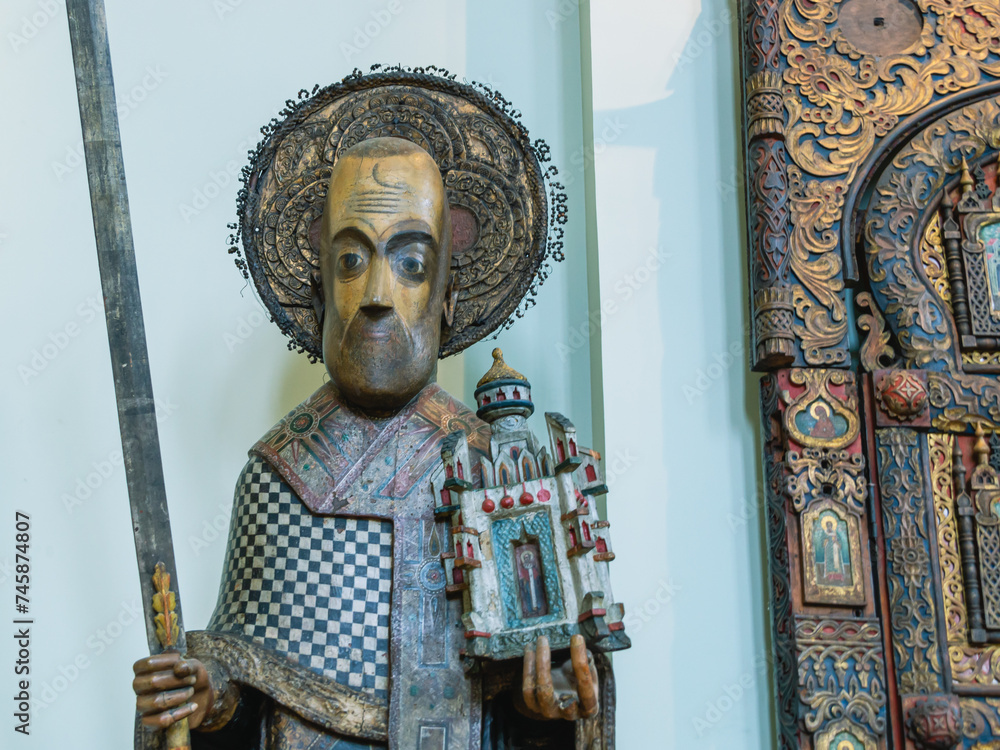 Obraz premium Perm wooden sculpture. A saint carved out of wood. Ancient sculptures in the church. The figure of a priest, carved from wood. Ancient masterpieces of wooden architecture. Religion and faith.