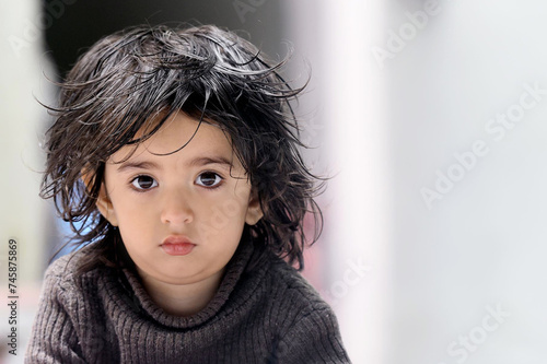 Fényképezés 3 years plus cute Asian Indian baby girl in open hair wearing brown high-necked sweater looking side wise looking in front in a shocking mood