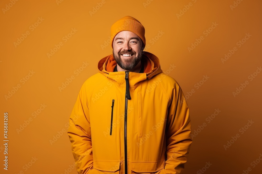 smiling bearded man in yellow hoodie and hat on orange background smiling bearded man in yellow hoodie and hat on orange background