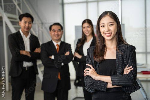 Portrait of young beautiful woman looking to camera in meeting room. She looking to camera with happy expression in her office with team. Business people concept.