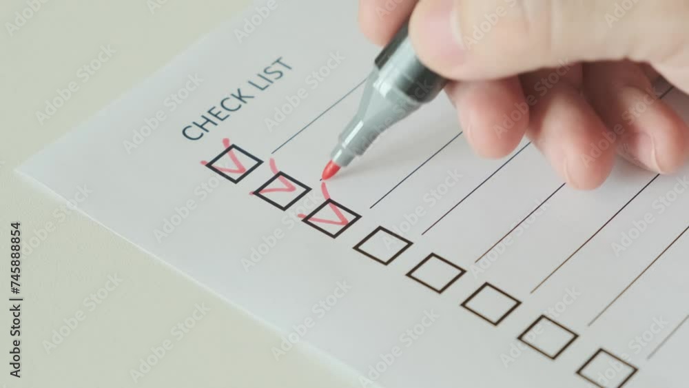 Hand with red pen marking on checklist box on paper, close-up, slow motion
