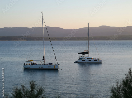Two sailing boats are anchored in the bay at Zlatni Rat. Soft evening light shortly before sunset. The island of Hvar can be seen in the background.
