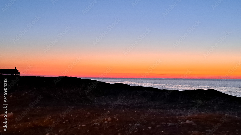 the sun dips below the horizon casting a warm golden glow across tranquil sea.