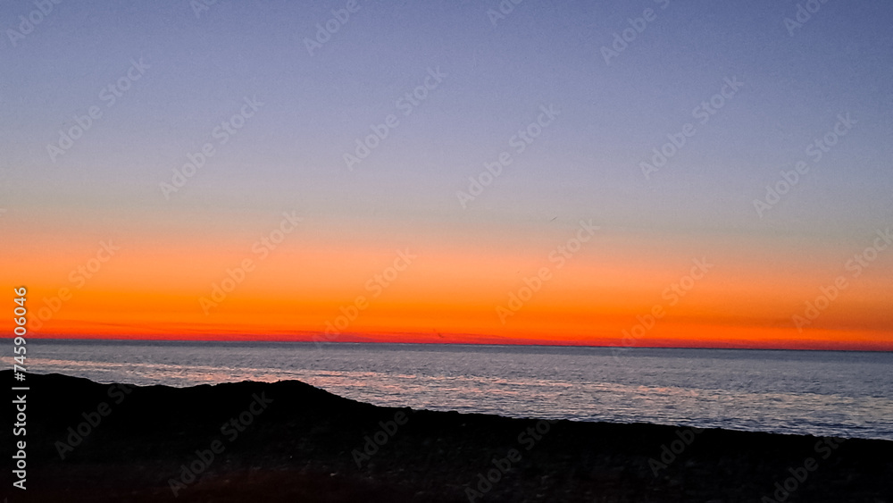 the sun dips below the horizon casting a warm golden glow across tranquil sea. the sun dips below the horizon casting a warm golden glow across tranquil sea.