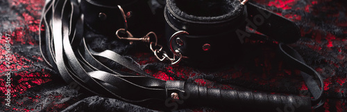 set of BDSM sex toys with handcuffs and whip flogger for submission and domination on a black background. Wide header cover for banner for sex shop