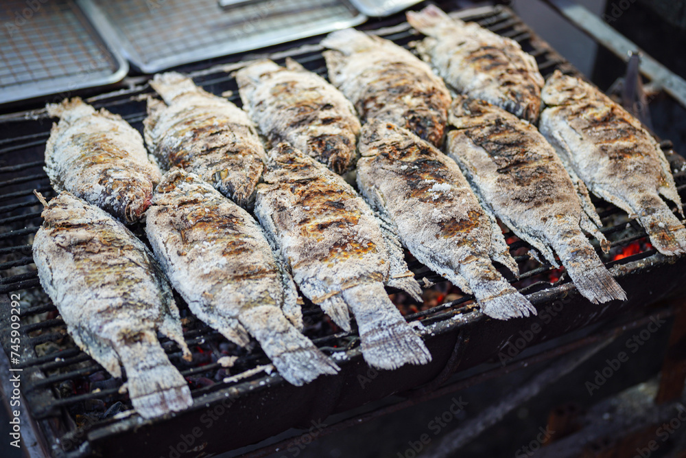 Group of fishes are grilling on the charcoal flame stove. Thai street food cooking and seafood menu photo, selective focus. Group of fishes are grilling on the charcoal flame stove. Thai street food cooking and seafood menu photo, selective focus.