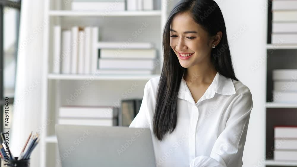 Attractive Asian businesswoman working on documents on laptop in office. Attractive Asian businesswoman working on documents on laptop in office.