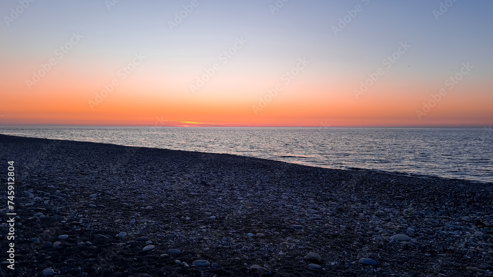 the sun dips below the horizon casting a warm golden glow across tranquil sea.