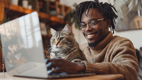 young black man with laptop sitting on desk in home office, pet accompanied on his laptop. Friendship between cat and owner. Best friends. 