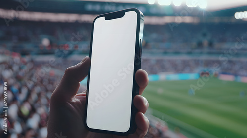 Man fan hands holding isolated smartphone device in soccer football crowed stadium game with blank empty white screen, sports betting concept