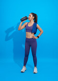 Asian Sporty young woman drinking protein shake isolated on blue background.