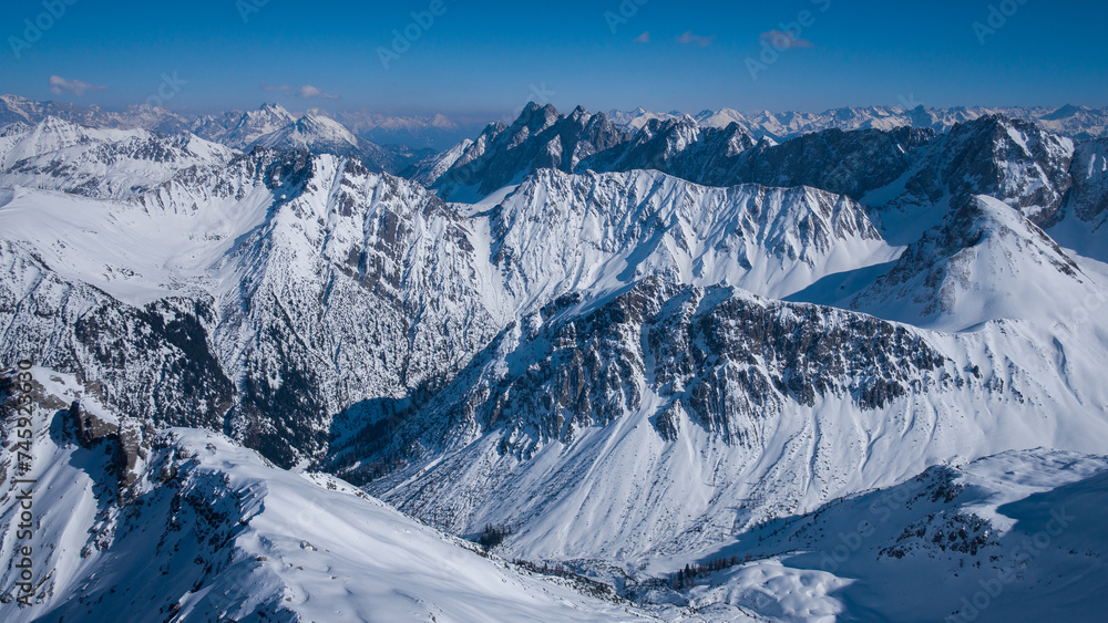Fototapeta premium Winter mountain panorama from mountain peak of Namloser Wetterspitze in Tyrol, Austria, sunny blue sky day.