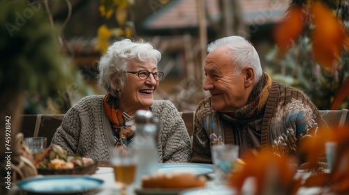 Joyful elderly couple sharing stories at family gathering, autumn backyard feast, golden years happiness, togetherness.
