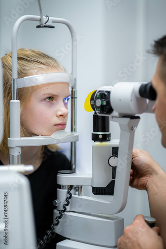 Fototapeta Naklejka Na Ścianę i Meble -  doctor and young patient in eye clinic, girl undergoing an eye test with professional optometrist using advanced diagnostic equipment, pediatric ophthalmology examination