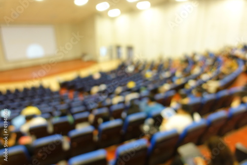 blurred or defocused people in the seminar convention hall. Business meeting for a press conference or lecturer education concept with a wide view from the room's corner. Modern, blurry auditorium.