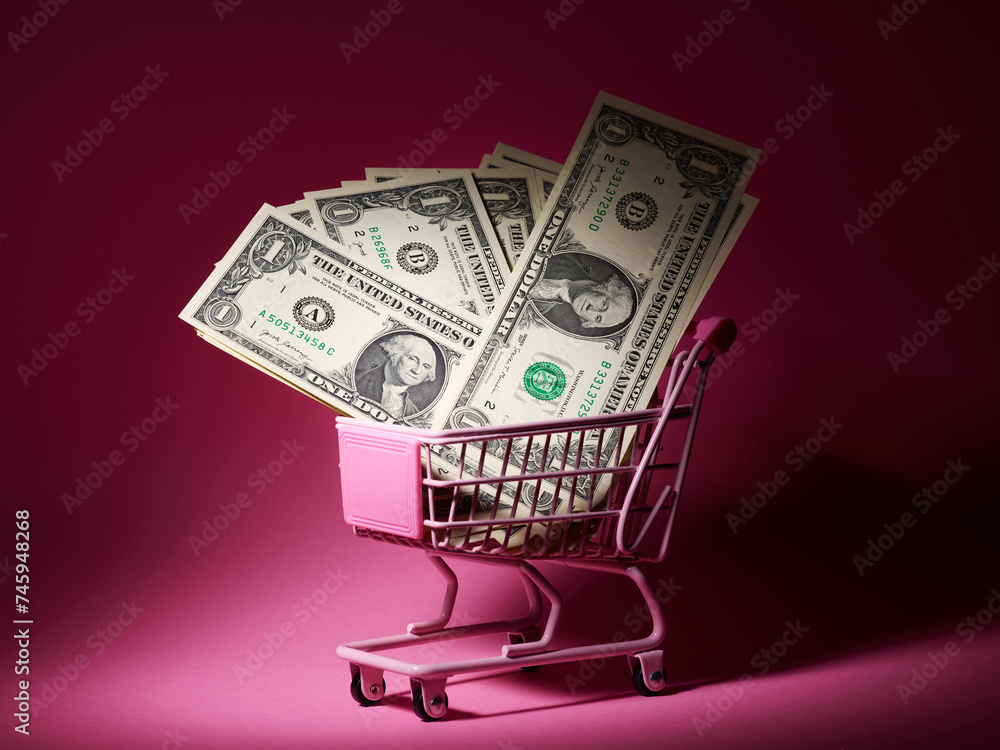 Shopping basket full of one dollar bills over pink backdrop Shopping basket full of one dollar bills over pink backdrop