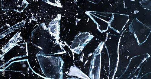 Super slow motion macro of window crystal glass panel is broken shattering in explosion with flying pieces isolated on black background at 1000 fps.