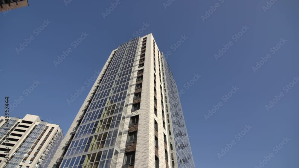 Building featuring glass balconies and windows stands in city. Apartments within towering structures boast glass windows housing population Building featuring glass balconies and windows stands in city. Apartments within towering structures boast glass windows housing population