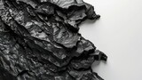 Top view of black coal with pieces in the form of waves, lines, and shapes separated on a white background with texture
