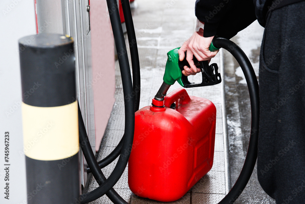 A man pouring fuel into a canister at a gas station. A man pouring fuel into a canister at a gas station.