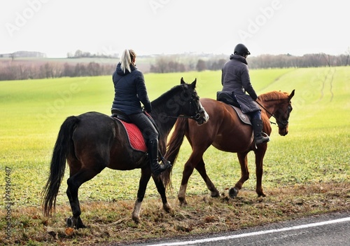Two young women are riding horses through a winter landscape