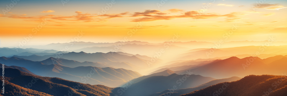 Panoramic view of a mountainous landscape enshrouded in the soft mist of early morning. Various shades of blue and grey layered effect. Light and shadow adds sense of tranquility to the scene.