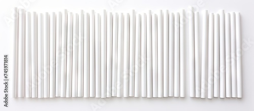 A cluster of white biodegradable eco-friendly paper drinking straws arranged neatly on a tabletop surface. The straws are resting still and untouched. photo