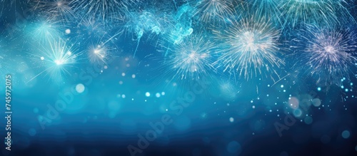 A vibrant blue background filled with fireworks bursting in the sky and blurry lights creating a festive atmosphere. Sparklers add a touch of excitement and celebration to this New Years Eve scene.