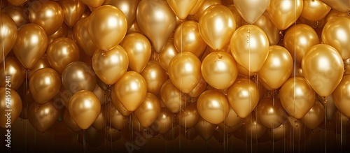 A collection of gold balloons suspended from the ceiling, creating a festive and celebratory atmosphere in the room. The balloons are clustered together, with shiny metallic surfaces reflecting light.