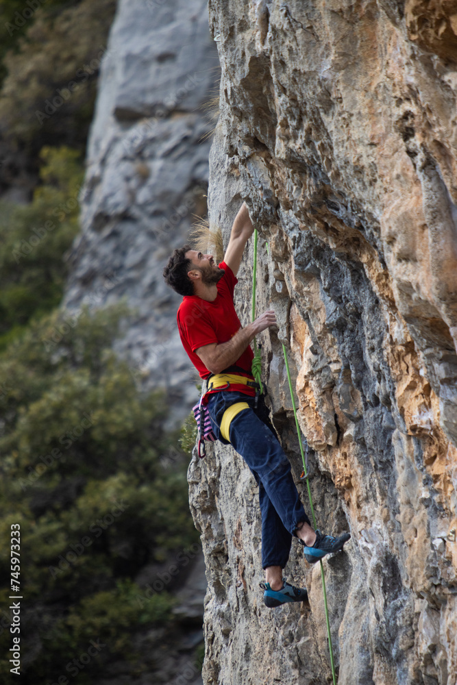 Man in red t-shirt scalded on gray wall, playing sports, reaching limit