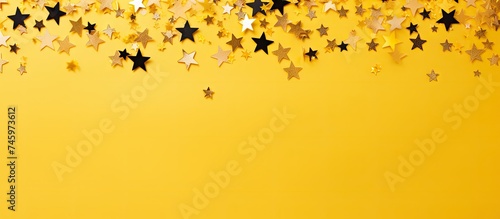 A festive yellow background adorned with scattered golden stars and crystals confetti. The image evokes a celebratory and vibrant atmosphere,