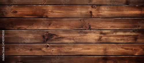 A close-up view of a wooden wall with a rich brown background. The texture of the wood is prominent, showcasing its grains and knots, while the deep brown color adds warmth to the overall aesthetic.