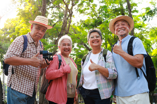 Portrait of a group of Asian elderly people traveling in a natural forest. They give thumbs up, likes and happy smiles. Elderly community