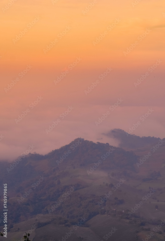 The stunning view from a tourist's standpoint as they go down a hill on a foggy trail with a hill and a background of a golden sky in Forest Park, Thailand. Rainforest. Bird's eye view. Aerial view. The stunning view from a tourist's standpoint as they go down a hill on a foggy trail with a hill and a background of a golden sky in Forest Park, Thailand. Rainforest. Bird's eye view. Aerial view.