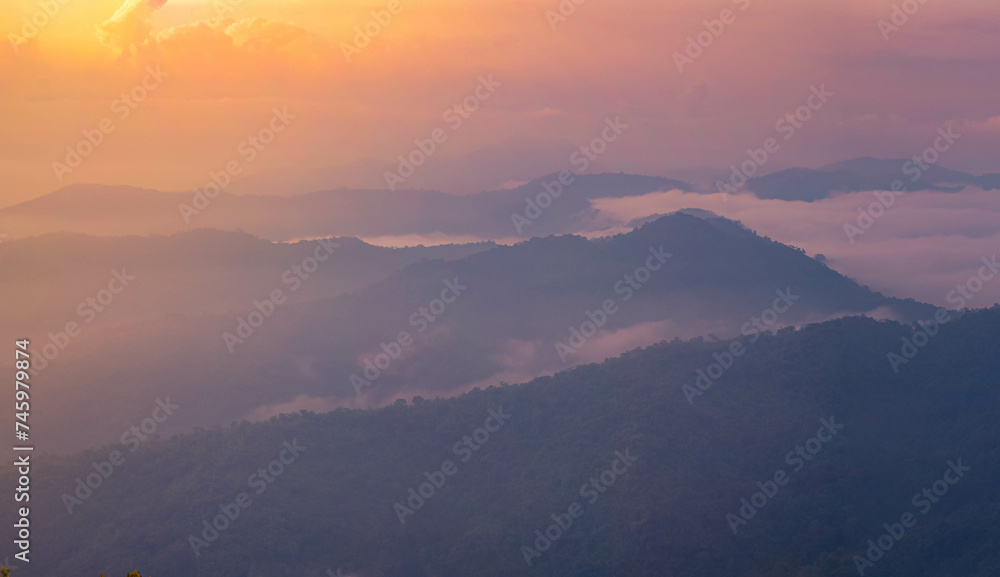The stunning view from a tourist's standpoint as they go down a hill on a foggy trail with a hill and a background of a golden sky in Forest Park, Thailand. Rainforest. Bird's eye view. Aerial view.	