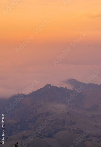 The stunning view from a tourist's standpoint as they go down a hill on a foggy trail with a hill and a background of a golden sky in Forest Park, Thailand. Rainforest. Bird's eye view. Aerial view.  © Thananchanok