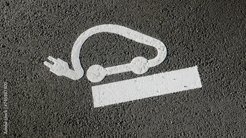Electric vehicle charging icon on pavement at parking lot on highway road photo