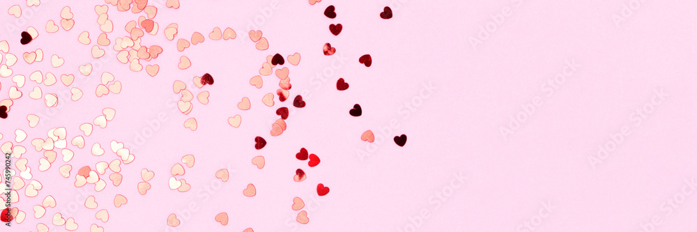 Banner with red confetti in a heart shape on a pink background. Concept with copy space.
