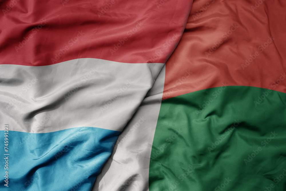 Obraz premium big waving national colorful flag of madagascar and national flag of luxembourg .
