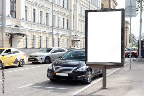 Billboard on a narrow city street with parked cars. Mock-up.
