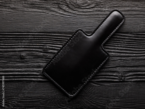 adult toy for sex over black wooden background. bdsm latex paddle for spanking
