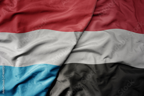 big waving national colorful flag of yemen and national flag of luxembourg .