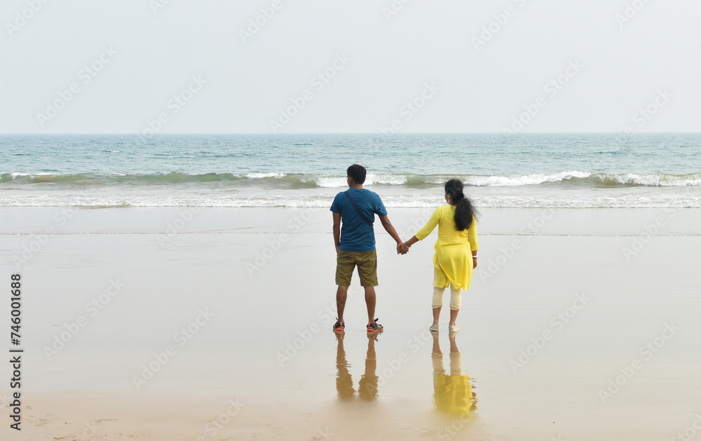 Happy honeymoon vacation at Lakshadweep, India. Indian couple relax on the white sand of the beach. Happy sea lifestyle. Young family, man, and woman rest on the beach of the ocean. 