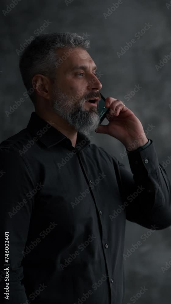 Serious guy in casual shirt talking by the smartphone in the modern loft office Serious guy in casual shirt talking by the smartphone in the modern loft office