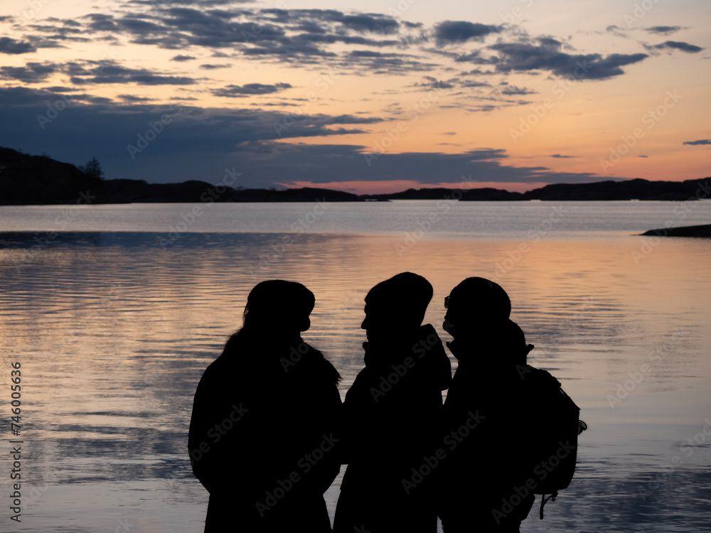 silhouette of four people on the beach at sunset with the setting sun