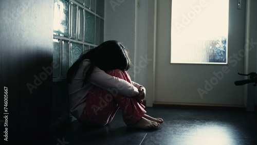Lonely depressed child covering face while sitting on corridor at home, dramatic scene of lonely little girl struggling with mental illness in childhood