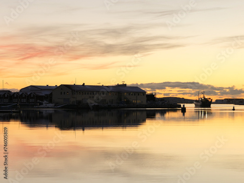 sunrise on the ocean with boats at dock and buildings in distance